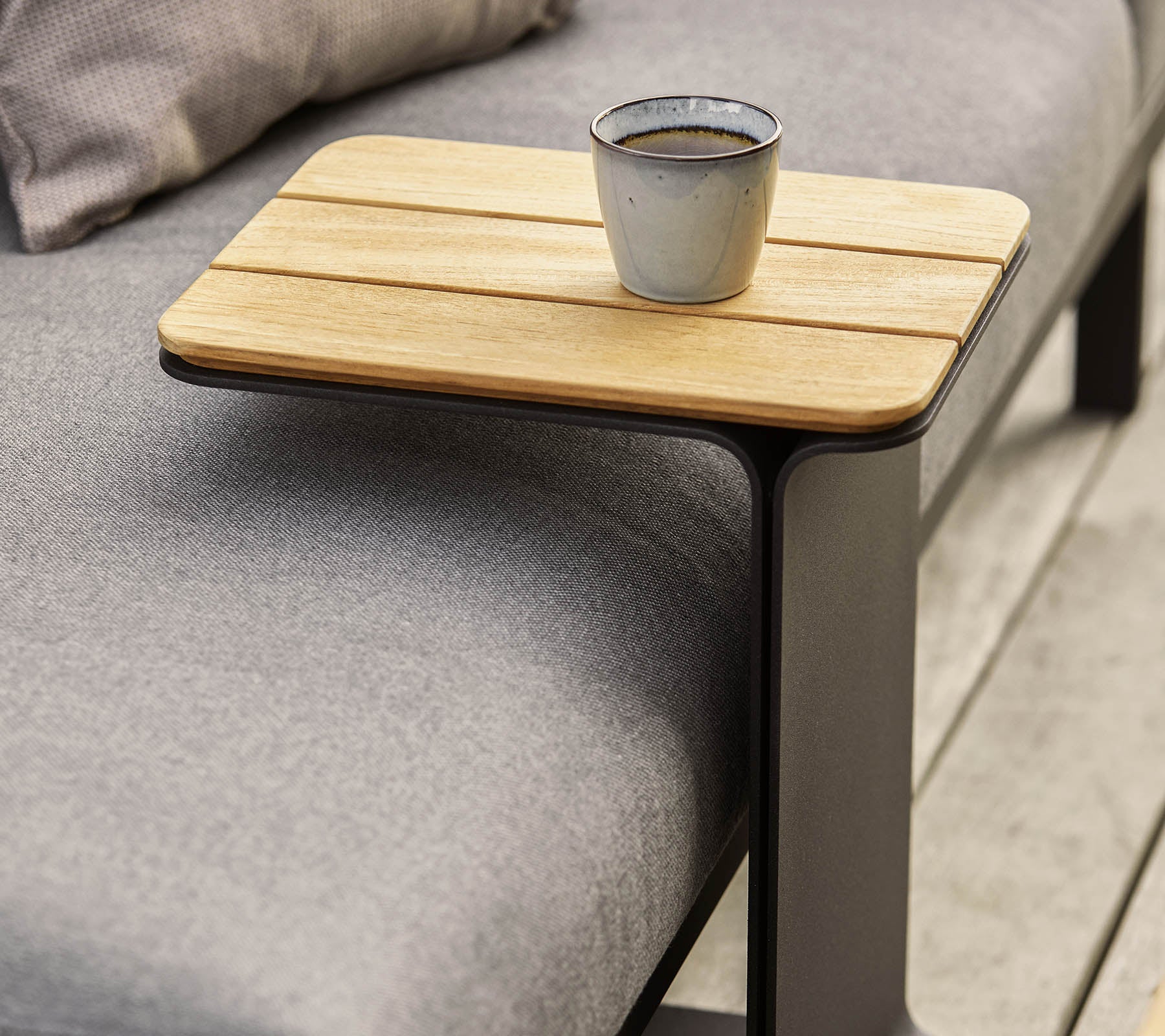A sleek side table featuring a wooden top and a modern metal frame, with a small cup placed on it.