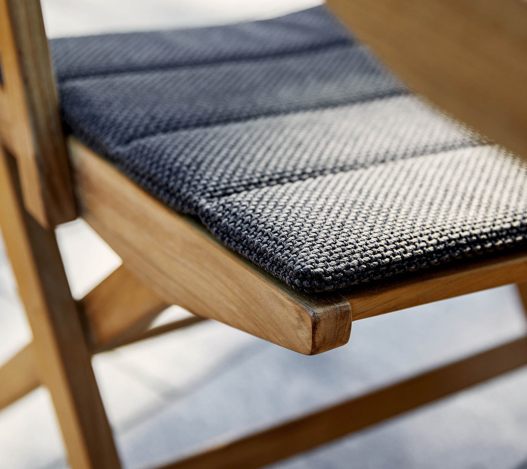 Close-up of a chair seat featuring a textured black and white fabric on a wooden frame, highlighting craftsmanship and detail.