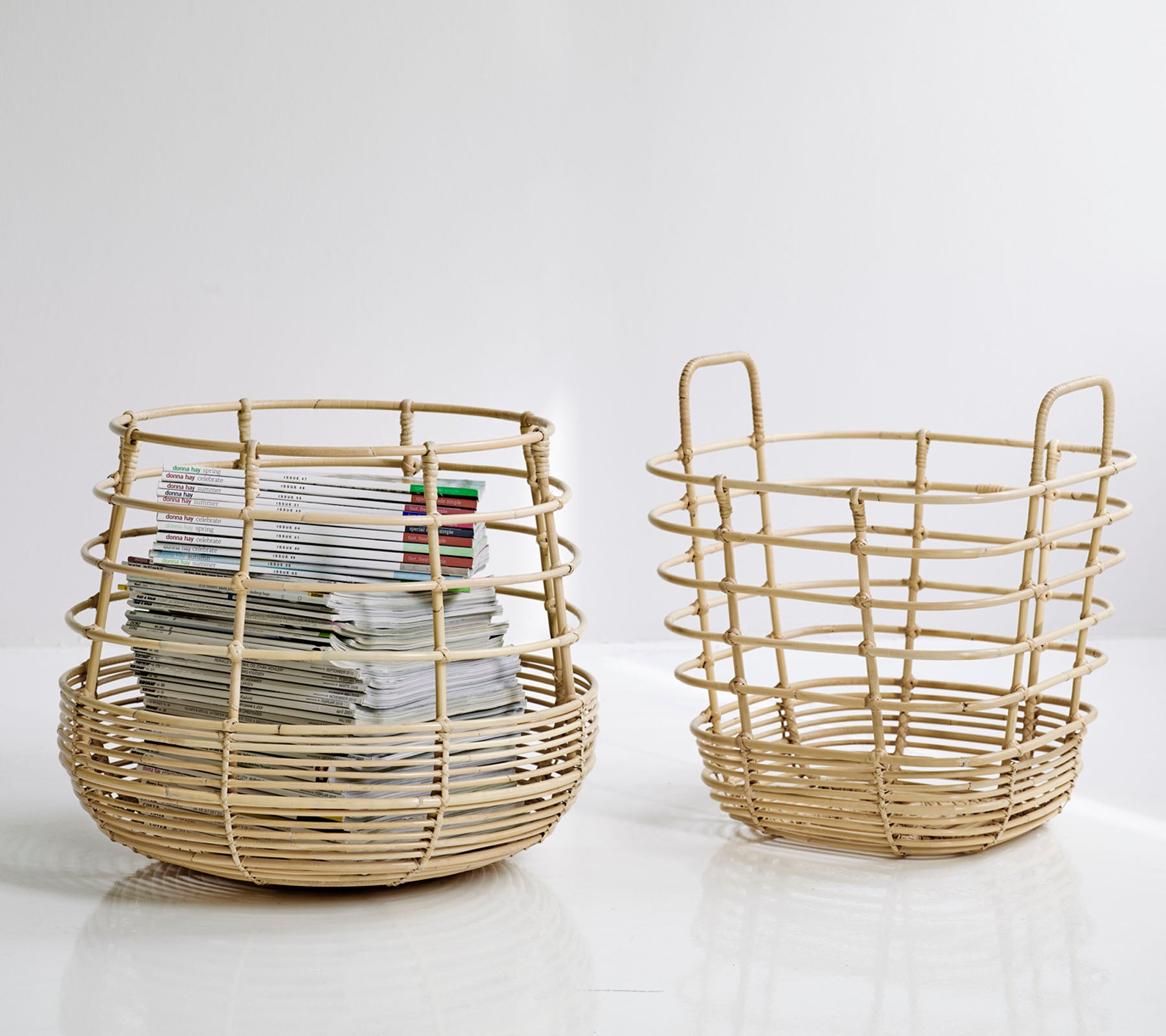 Two woven storage baskets, one larger and round with papers inside, and a smaller, open design beside it, both in a natural color.