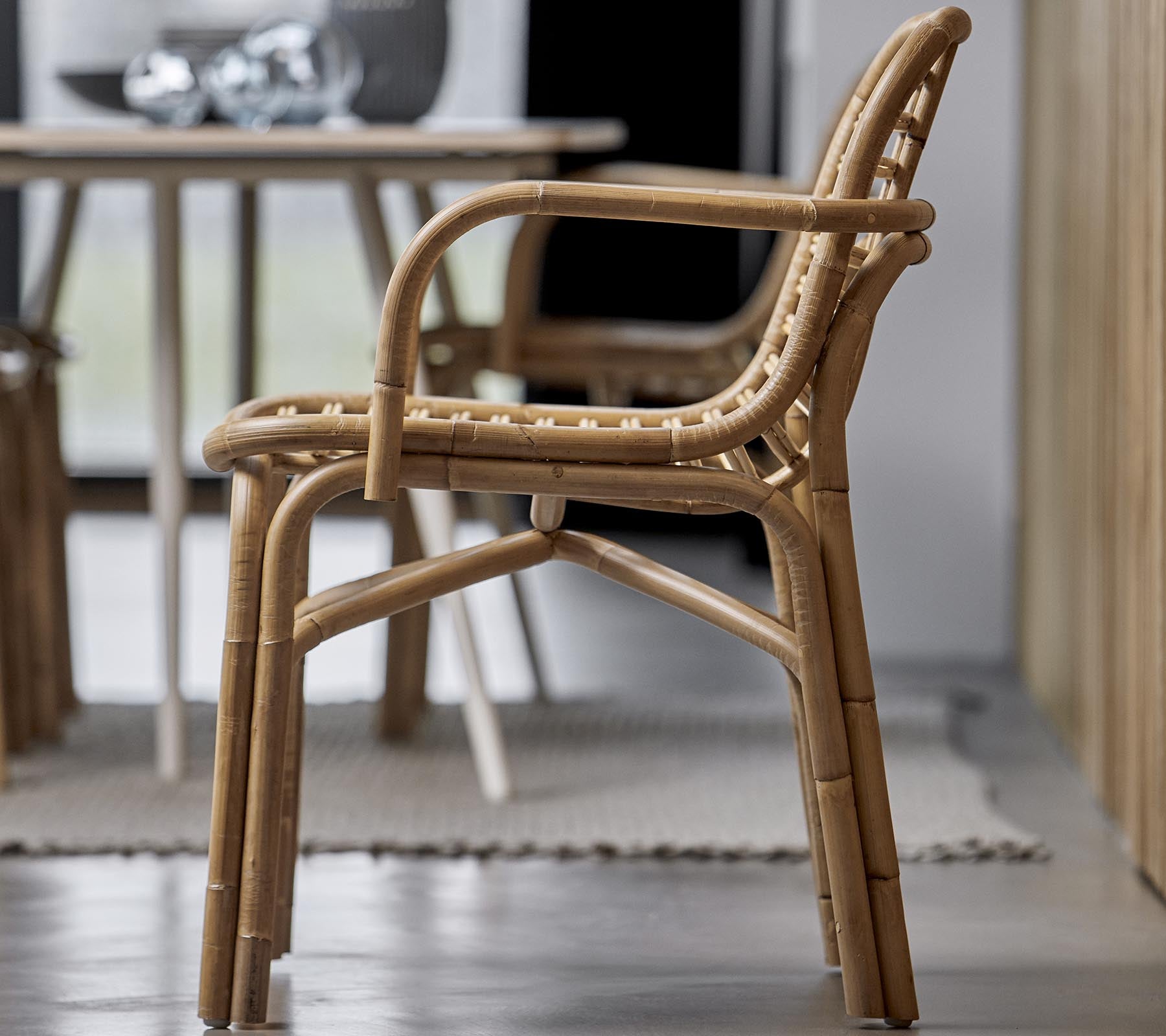 A stylish chair made of natural materials, featuring a woven design and armrests, suitable for various interior settings.
