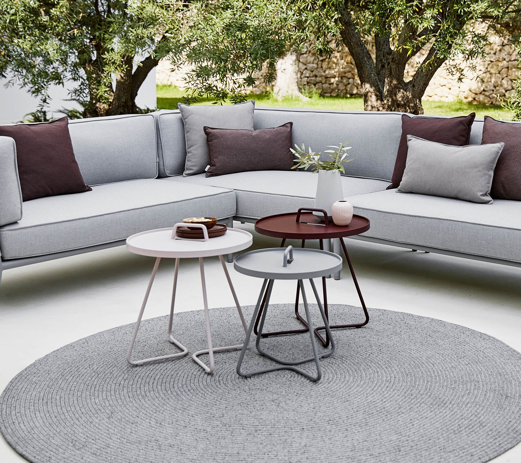Stylish outdoor seating area featuring a sectional sofa with cushions and modern round coffee tables in a relaxed, contemporary setting.