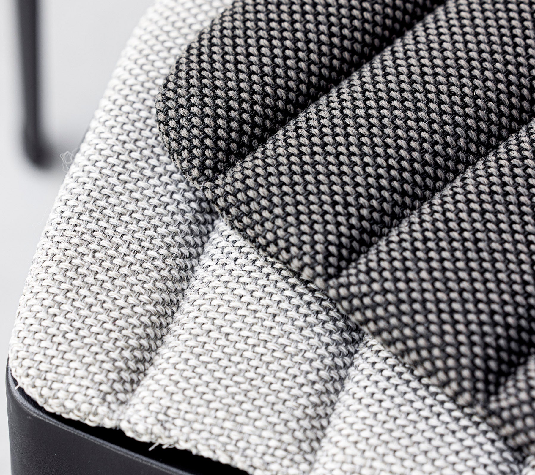Close-up of a textured fabric seat, showcasing a mix of light and dark gray woven patterns with a modern design. Ideal for contemporary interiors.