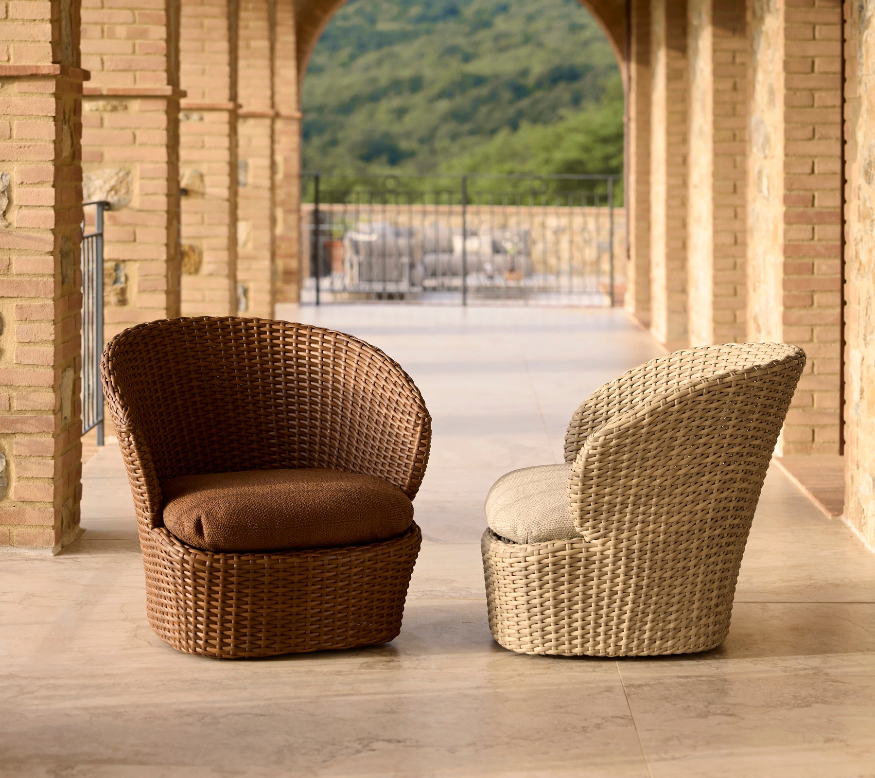 Two stylish coast lounge chairs in brown and cream wicker, featuring comfortable cushions and a modern design.