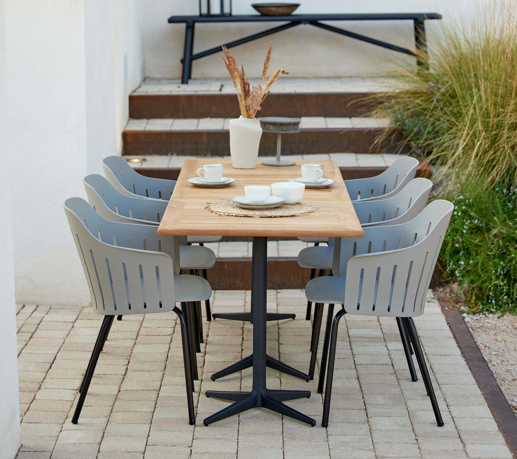 A stylish dining setup featuring a wooden table surrounded by gray chairs, complemented by decorative items and greenery.