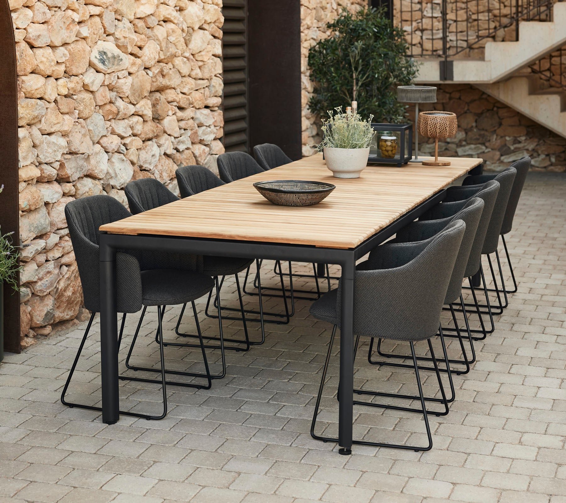 Elegant dining table with a wooden top and black metal legs, surrounded by grey chairs, perfect for gatherings.