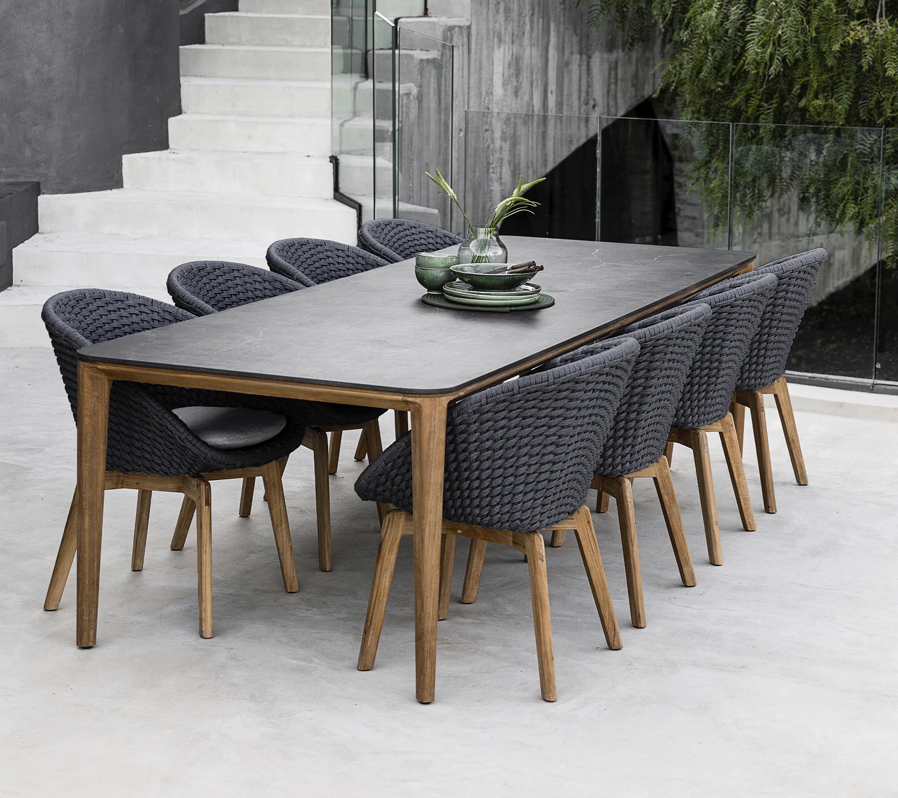A modern table surrounded by eight stylish chairs, adorned with decorative plants on the table in a sleek, minimalist setting.
