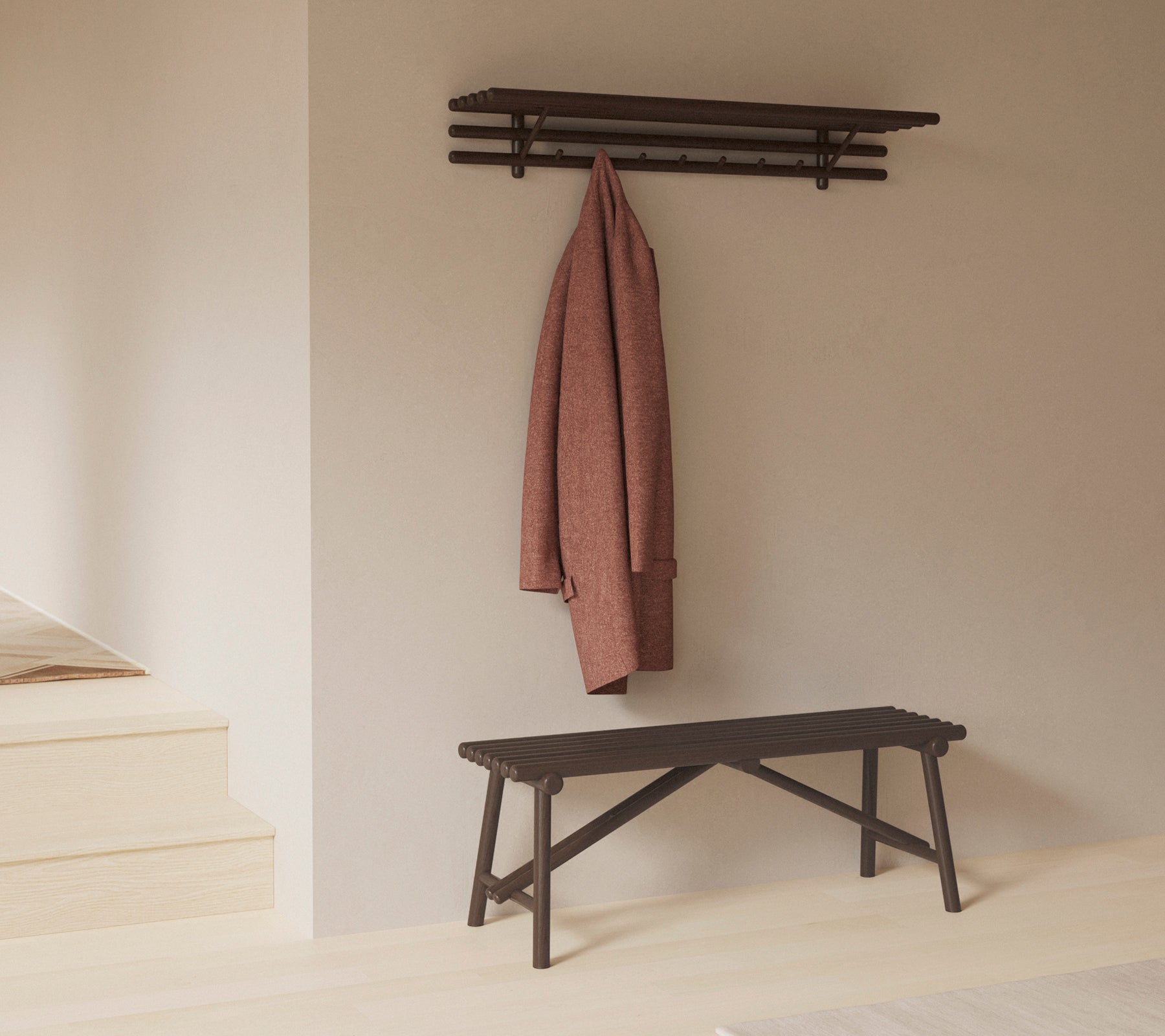 A minimalist bench with a shelf above, showcasing a coat hanging on hooks, emphasizing simplicity and functionality in design.