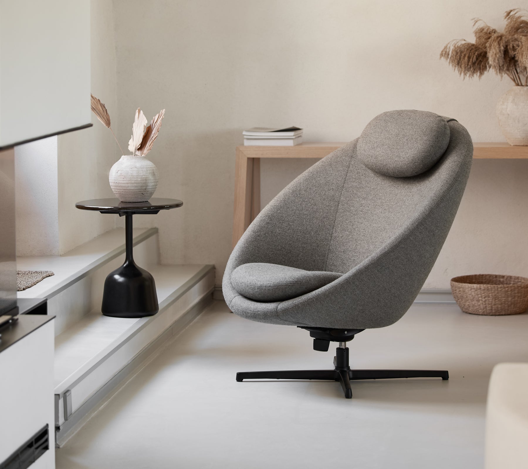 Stylish gray chair with a curved shape and supportive headrest, complemented by a minimalist side table and decorative elements.