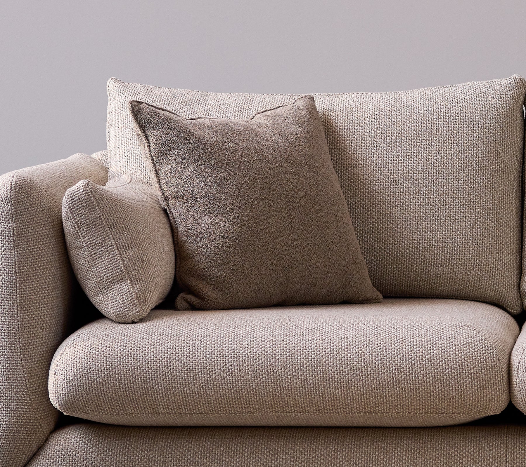 Taupe scent scatter cushion on a soft, textured sofa, adding a cozy and stylish touch to the seating area.