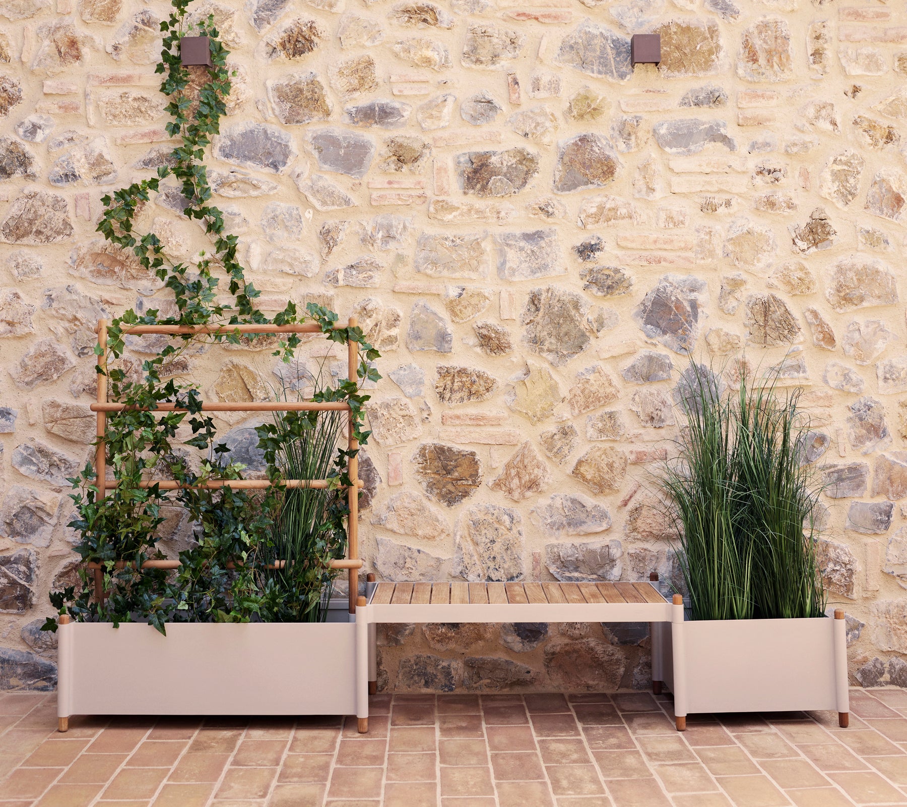 Sticks planter bench with greenery against a stone wall, featuring a vertical plant stand and two large planters.